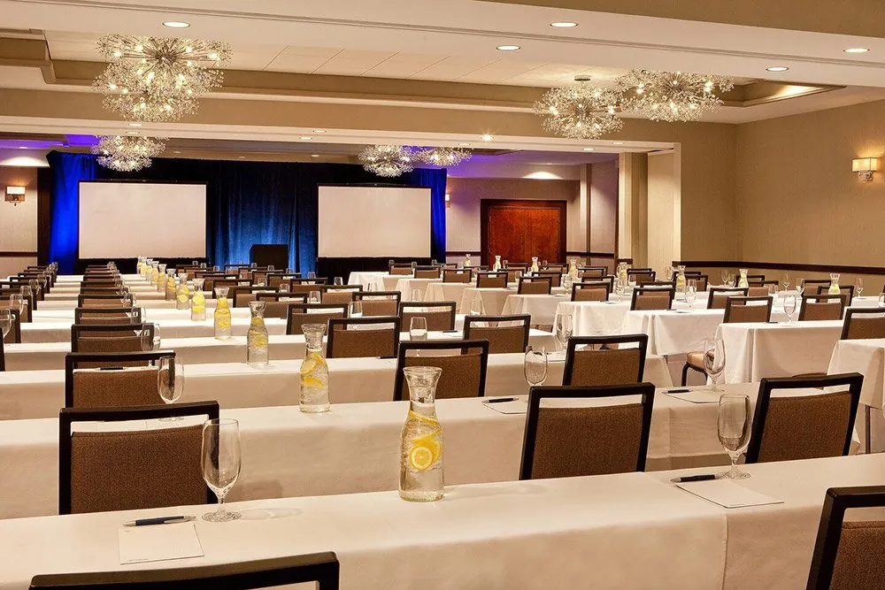 A conference room set classroom-style with chandeliers and presentation screens